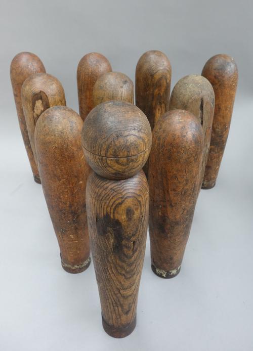 An early 20th century ten pin pine skittle set, with wrought iron band to the bases, with five wooden balls, (a.f).