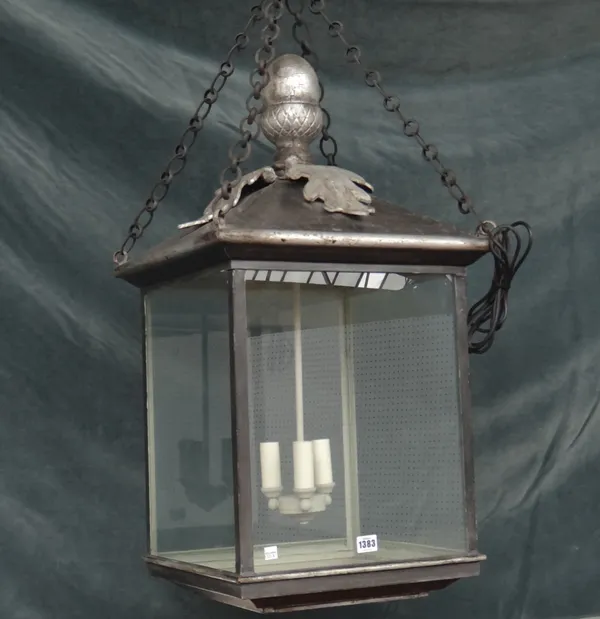 A modern silvered metal hall lantern of square form with an acorn finial, pitch roof and internal three light fitment. 80cm high