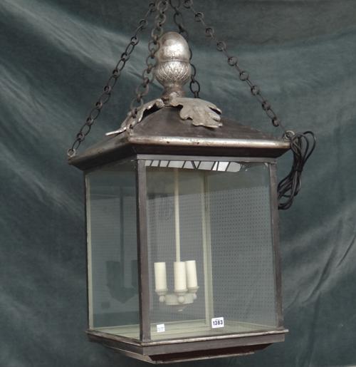 A modern silvered metal hall lantern of square form with an acorn finial, pitch roof and internal three light fitment. 80cm high