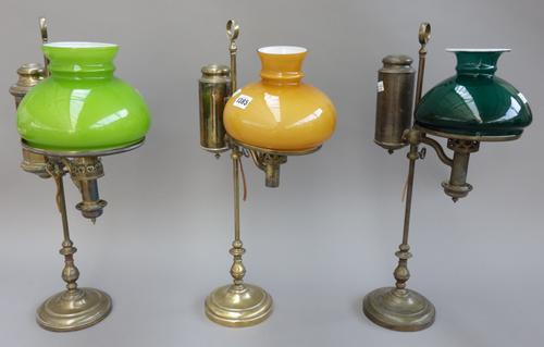 An Edwardian brass oil lamp (converted), the label detailed 'Salon & Co, London & Edinburgh', with loop handle, glass shade and loaded circular base,