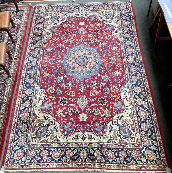 An Esfahan carpet, Persian, the madder field with a pale indigo foliate roundel, ivory spandrels, all with delicate floral sprays, an indigo complemen