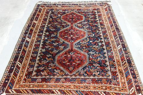 A Khamseh rug, South Persian, the indigo field with three madder medallions, all covered with chickens and sheep, various borders, 218cm x 172cm.