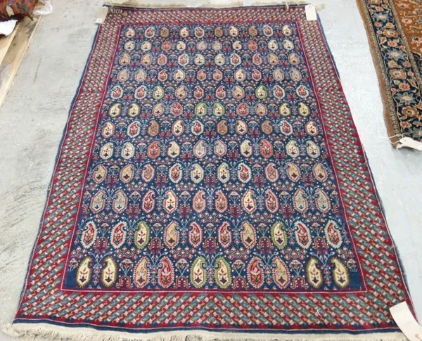 A Hereke rug, Turkish, the indigo field with an allover boteh design, minor floral sprays, a banded border, 182cm x 122cm.