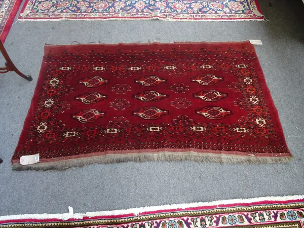 A Kizyk Ayak Jural, the madder field with three rows of three guls, supporting hooked crosses, a madder hooked motif border, skirt end, 99cm x 169cm.