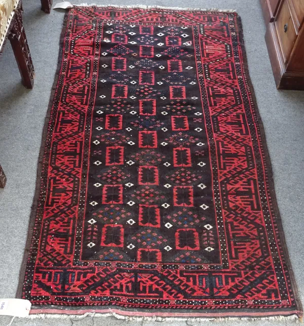 A Baluchistan rug, the dark brown field with columns of diamonds and squared flower motifs; a madder angular waved vine border, 165cm x 94cm.