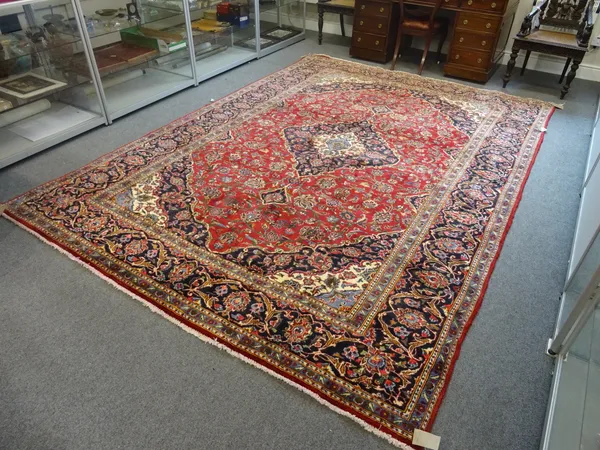 A Sarough carpet, Persian, the madder field with a gold dark indigo and ivory medallion, matching spandrels, all with delicate floral sprays, a comple