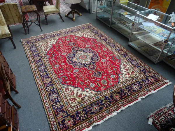 An Heriz carpet, Persian, the madder field with a bold indigo and ivory medallion, floral ivory spandrels, all with angular floral sprays, a dark indi