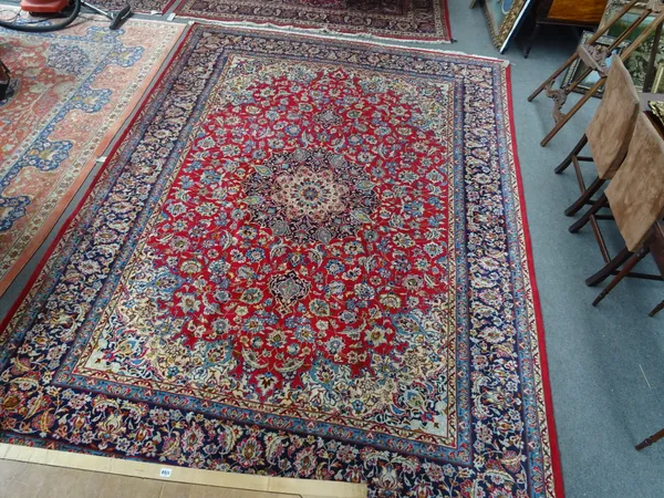 An Esfahan carpet, Persian, the madder field with an ivory and indigo sunburst medallion, ivory spandrels, all with abundant floral palmette vine and