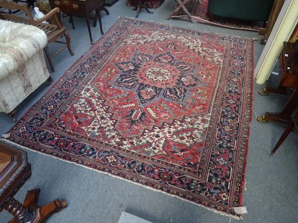 A Heriz carpet, Persian, the madder field with a bold indigo medallion, ivory and madder spandrels, all with angular leaves and sprays; an indigo palm