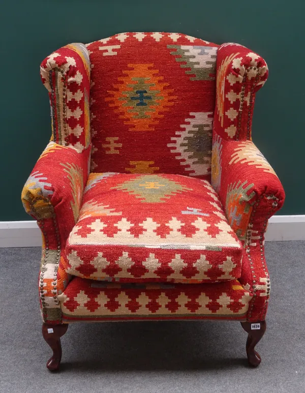 A pair of mid-18th century style wingback armchairs, in Tabriz carpet upholstery, on squat cabriole supports, 90cm wide x 108cm high, (2).