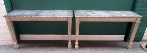 A pair of console tables, each with rectangular faux marble top on a pair of grey painted tapering square supports, with carved bellflower decoration,