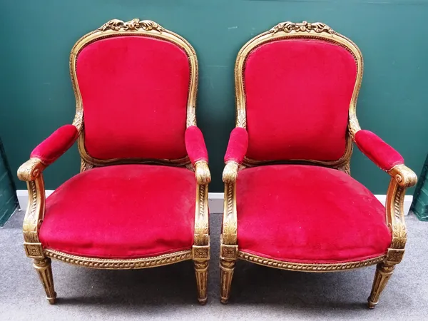 A pair of late Victorian gilt framed open armchairs, each with bow seat on tapering fluted supports, 75cm wide x 116cm high, (2).