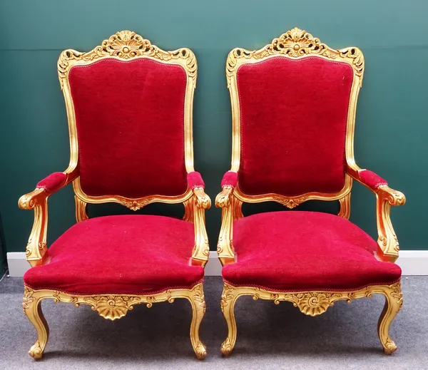 A pair of 20th century carved and pierced gilt framed open arm throne chairs, with serpentine seat on scroll supports, 80cm wide x 132cm high, (2).