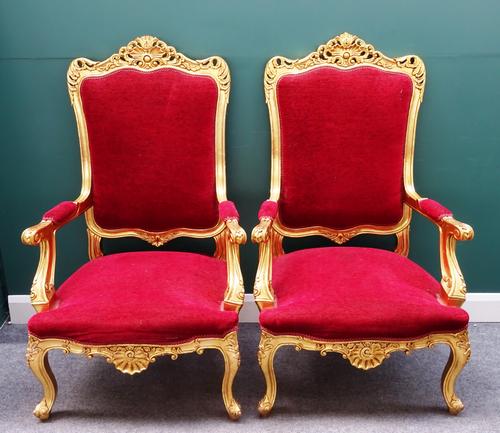 A pair of 20th century carved and pierced gilt framed open arm throne chairs, with serpentine seat on scroll supports, 80cm wide x 132cm high, (2).