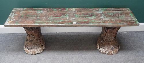A 20th century bench, the rectangular hardwood top on a pair of faux carved elephant feet, 150cm wide x 46cm high x 37cm deep.
