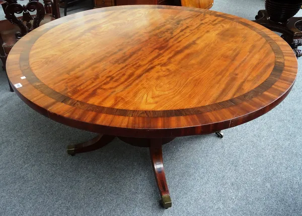 A late George III rosewood banded mahogany centre table, the circular snap top on turned column and four downswept supports, 143cm diameter x 73cm hig