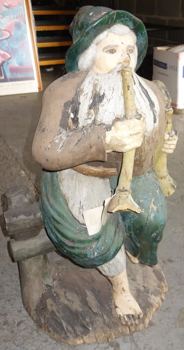 A carved and painted figure of a seated gnome, blowing his horn, 95cm high. K5