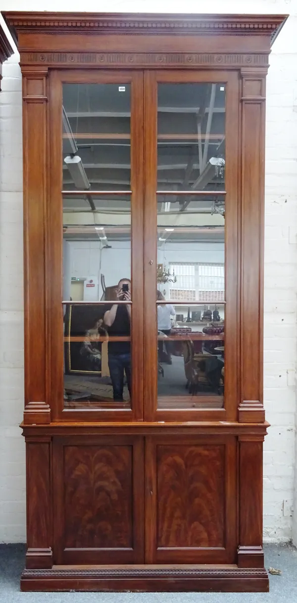 An 18th century style hardwood display cabinet cupboard, the dentil cornice over a pair of glazed doors and further lower panelled cupboards, on plint