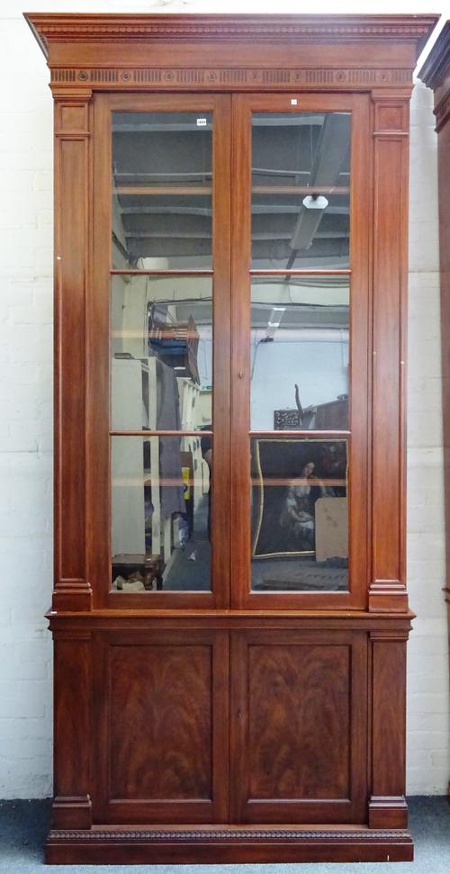 An 18th century style hardwood display cabinet cupboard, the dentil cornice over a pair of glazed doors and further lower panelled cupboards, on plint