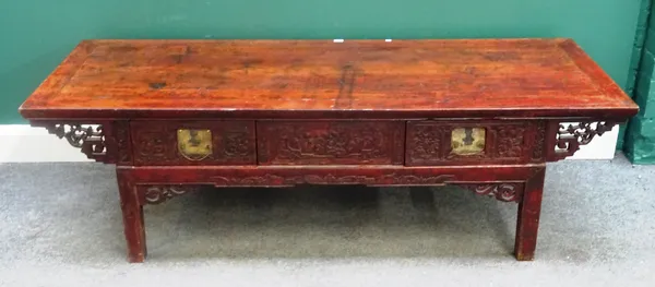 A 20th century Eastern red lacquered hardwood low table, the carved frieze with three drawers, on block supports, 168cm wide x 62cm deep x 50cm high.