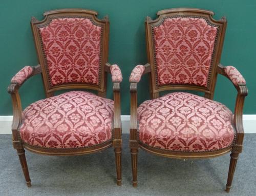 A pair of Louis XVI style walnut framed open armchairs, each with bow seat on tapering fluted supports, 56cm wide x 89cm high, (2).