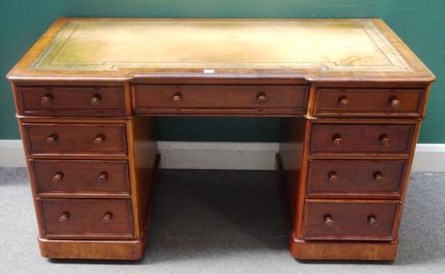 A Victorian mahogany pedestal desk, the inverted breakfront top over nine drawers about the knee, 137cm wide x 77cm high x 69cm deep.