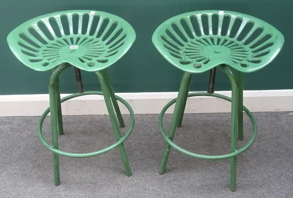 20th century design; a pair of green painted metal stools with tractor style seats, each 50cm wide x 68cm high, (2).