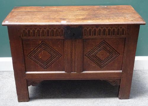 A 17th century oak coffer, the plank top over a double panel front, on stile feet, 96cm wide x 87cm high x 43cm deep.