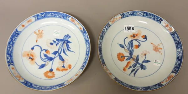 A pair of Chinese Imari plates, first half 18th century, each painted with flowers and an insect beneath a blue foliate border reserved with floral pa