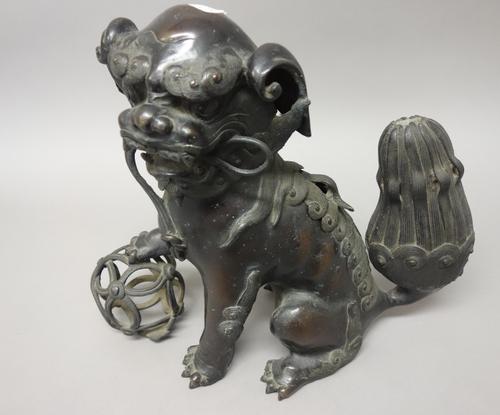 A Chinese bronze dog of fo censer and cover, 19th century, modelled seated with one paw resting on a pierced ball, 31cm. high