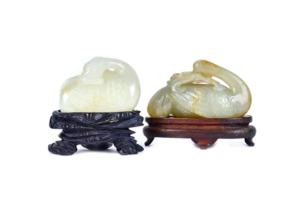 A Chinese jade carving of a bird, carved with its head turned over its back and holding a branch of fruiting peach in its mouth, the stone of celadon