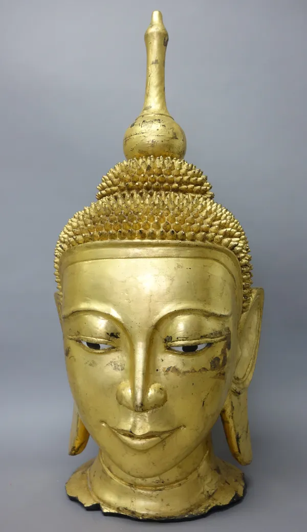 A large gilt composition head of Buddha, modelled with serene expression and with painted eyes, 75cm. high