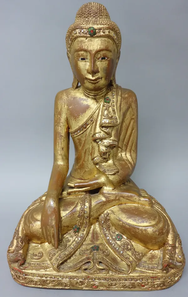 A Burmese giltwood Buddha, late 19th/ 20th century, seated in dhyanasana with hands in bhumisparsa, inlaid coloured glass details, 41cm. high.