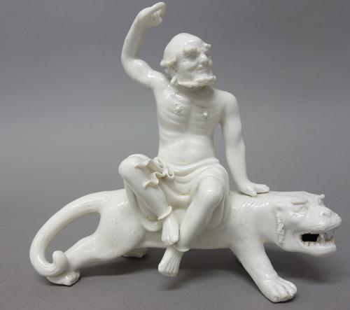 A Chinese blanc-de-chine group, 20th century, modelled as a luohan seated on the back of a prowling tiger, impressed double gourd mark, 18cm. length.
