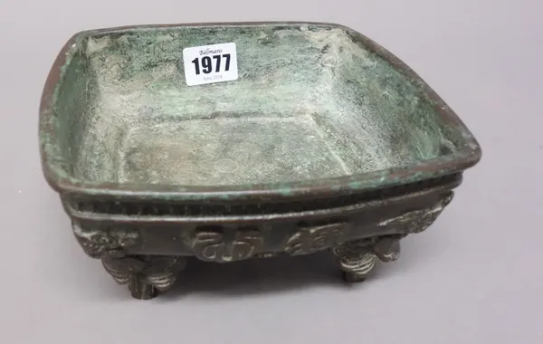 A Chinese bronze censer, probably 19th century, of swollen square form, the sides decorated in relief with two characters and cloud scrolls, raised on