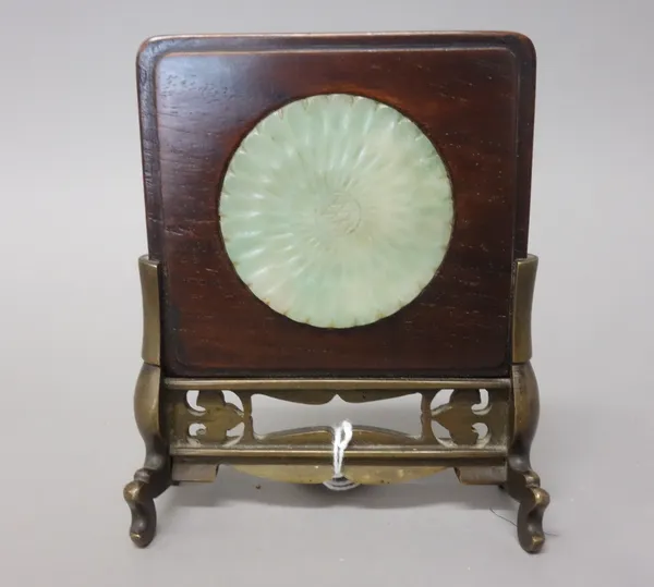 A Chinese jade circular plaque, carved as a chrysanthemum, inset into a wood frame and bronze stand, overall height 12.5cm.