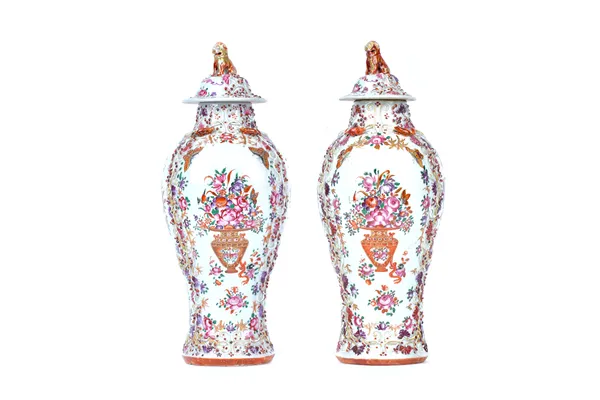 A pair of Chinese famille-rose baluster vases and covers, Qianlong, each painted with baskets of flowers within moulded and applied squirrel and vine