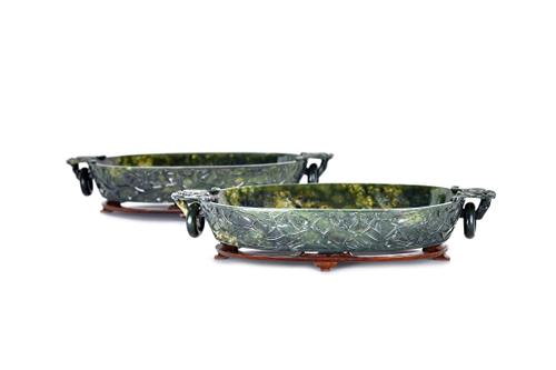 A pair of Chinese spinach jade washers, late 19th/early 20th century, of oval form set with bat and ring handles, the exteriors carved with blossoming