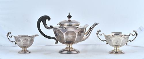 A silver composite three piece tea set, comprising; a teapot, with black composition fittings, a twin handled sugar bowl and a milk jug, each piece of