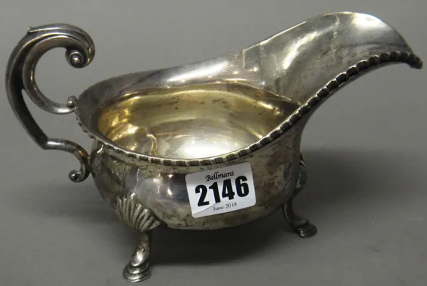 A silver sauceboat, decorated with a gadrooned rim, with a scrolled handle, raised on three pad feet, London 1902, weight 380 gms.