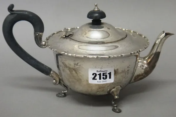 A silver teapot, of compressed circular form, having a decorated rim, raised on three pad feet, with black fittings, Birmingham 1920, gross weight 349