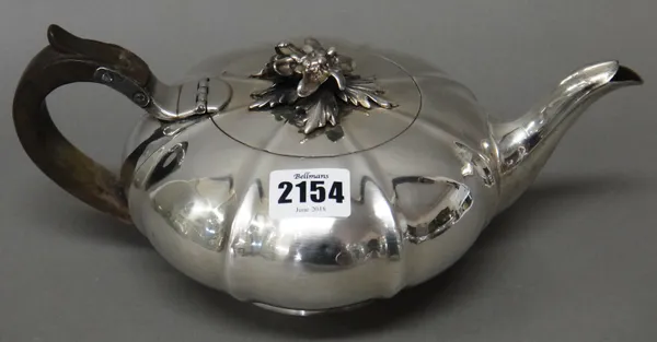 A George IV silver teapot, of compressed melon shaped form, the hinged lid with a cast floral and foliate finial, raised on a circular foot, with a wo