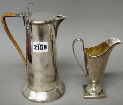 Silver, comprising; a hot water jug, of tapering cylindrical form, having a rush-work handle, London 1904 and a silver milk jug, of helmet shaped form