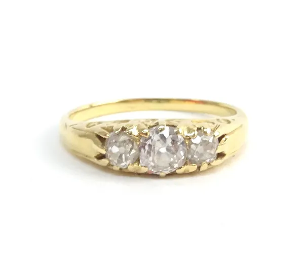 A gold and diamond set three stone ring, mounted with cushion shaped diamonds and with the principal diamond mounted to the centre, ring size M, with