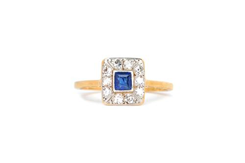 A gold and platinum, sapphire and diamond rectangular cluster ring, claw set with the emerald cut sapphire at the centre, in a surround of ten circula