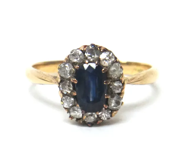 A gold, sapphire and diamond oval cluster ring, claw set with the oval cut sapphire in a surround of cushion shaped diamonds, detailed indistinctly 58