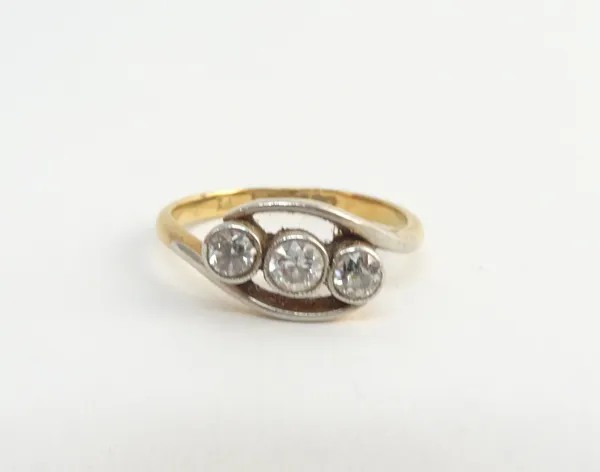 A gold and platinum, diamond set three stone ring, mounted with a row of cushion shaped diamonds, in a crossover design, detailed 18 CT PT, ring size