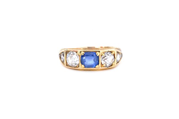 A gold, sapphire and diamond ring, mounted with the cushion shaped sapphire at the centre, between the two principal cushion shaped diamonds, between