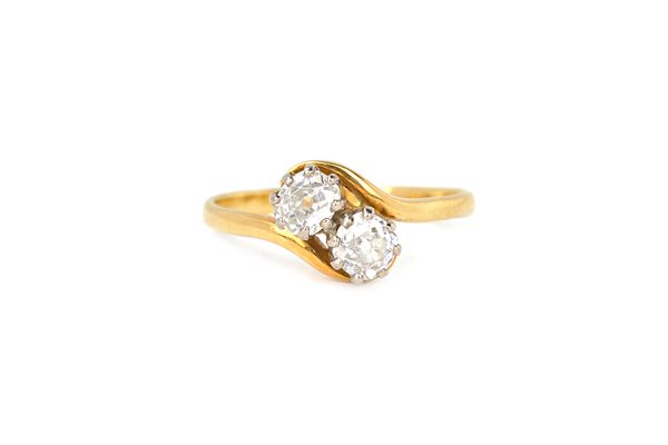 A gold and diamond two stone ring, claw set with cushion shaped diamonds in a crossover design, detailed 18 CT, ring size N and a half, with a case. I