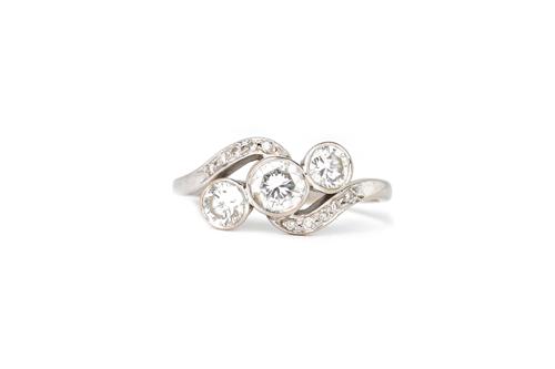 An 18ct white gold and diamond three stone ring, collet set with the three principal circular cut diamonds, in a crossover design, between diamond set